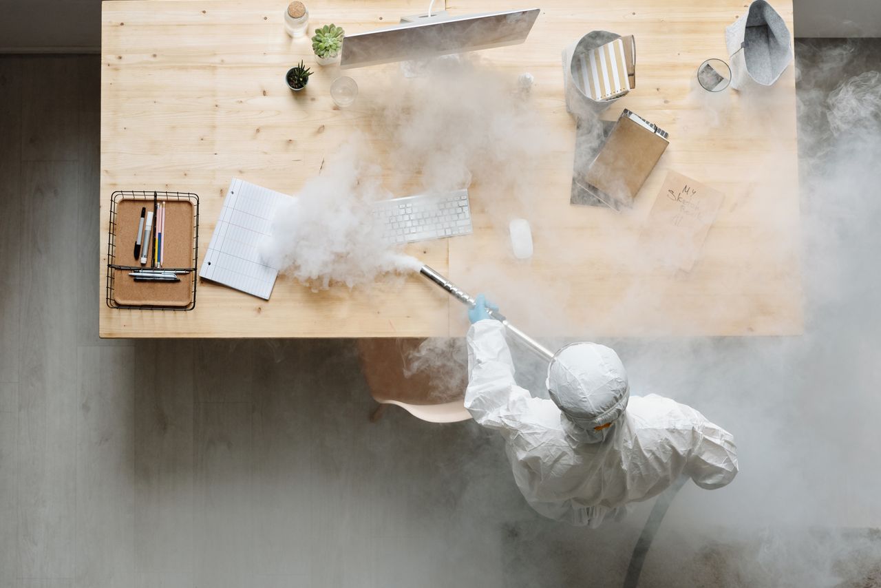 why-choose-us An individual disinfects a workspace using fumigation, wearing full protective gear for safety.